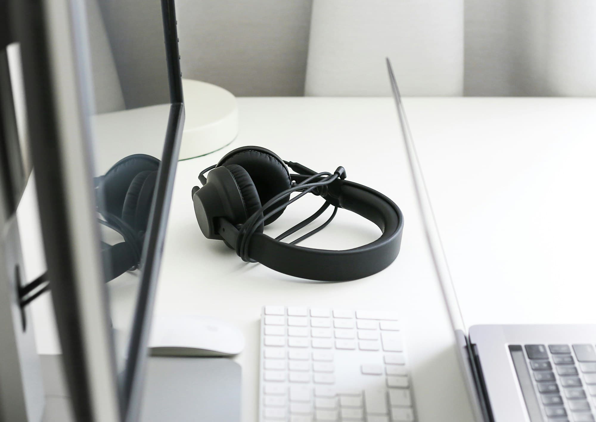 Casque audio posé sur un bureau, à côté d'un clavier et d'un ordinateur portable