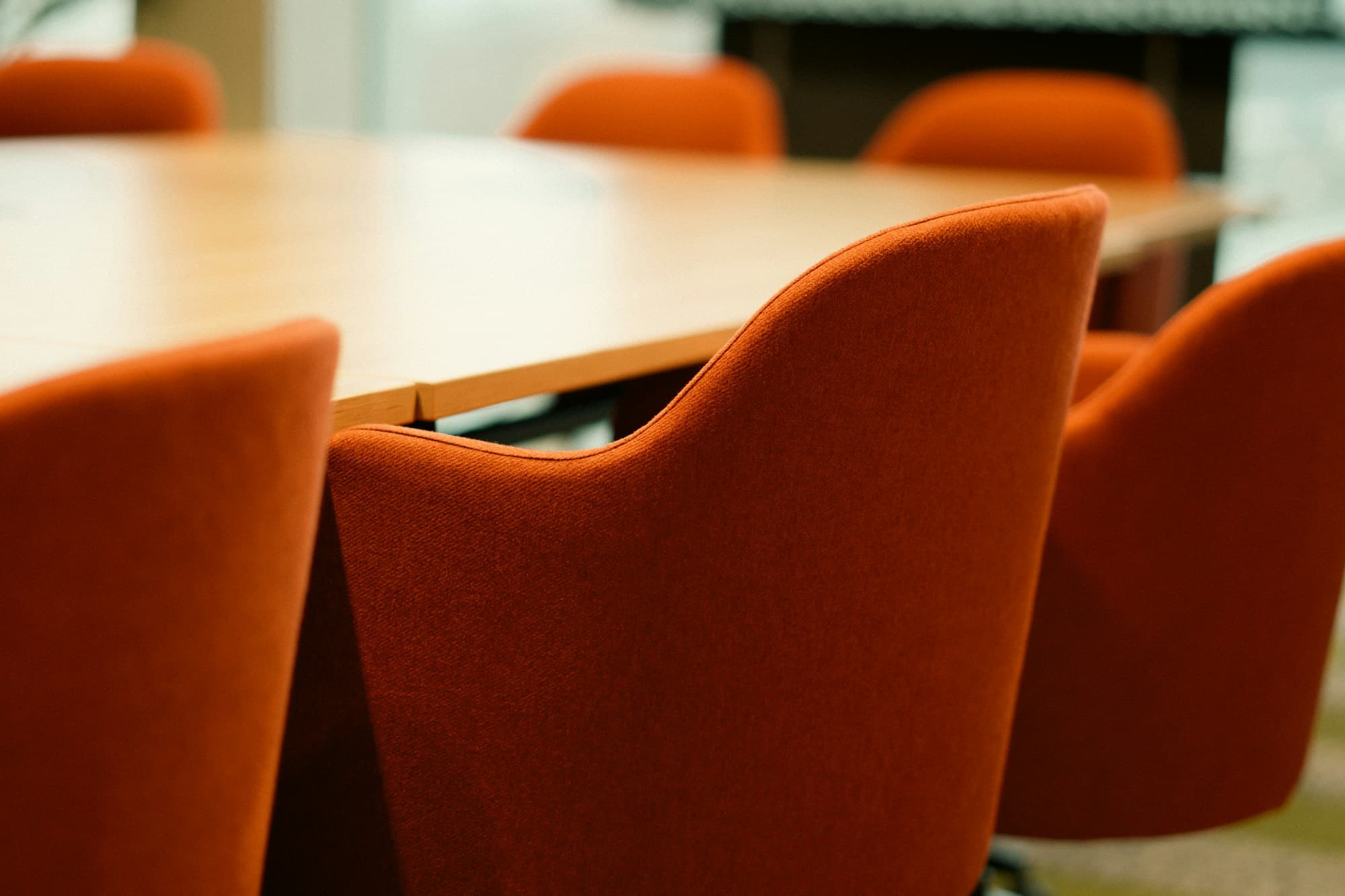 Chaises corail autour d'une table de réunion en bois, salle vide